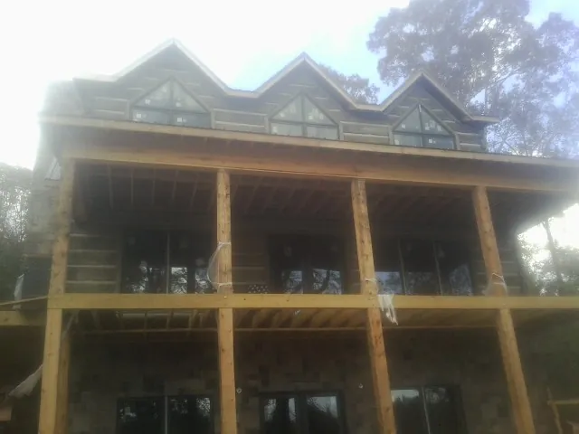Dormers and porch framing on a large log home under construction — Roof Coating work by our crew in Scotts Hill