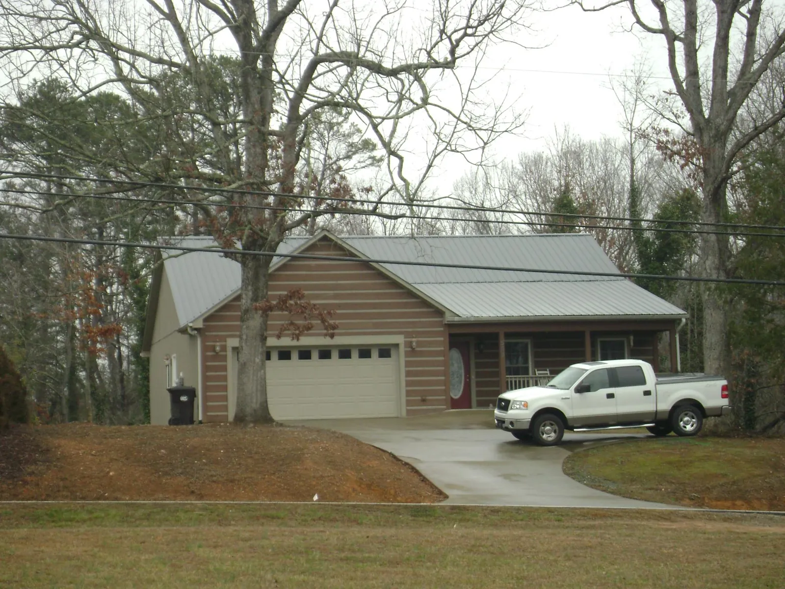 Gray metal roof on a log sided house with an attached two car garage in Scotts Hill