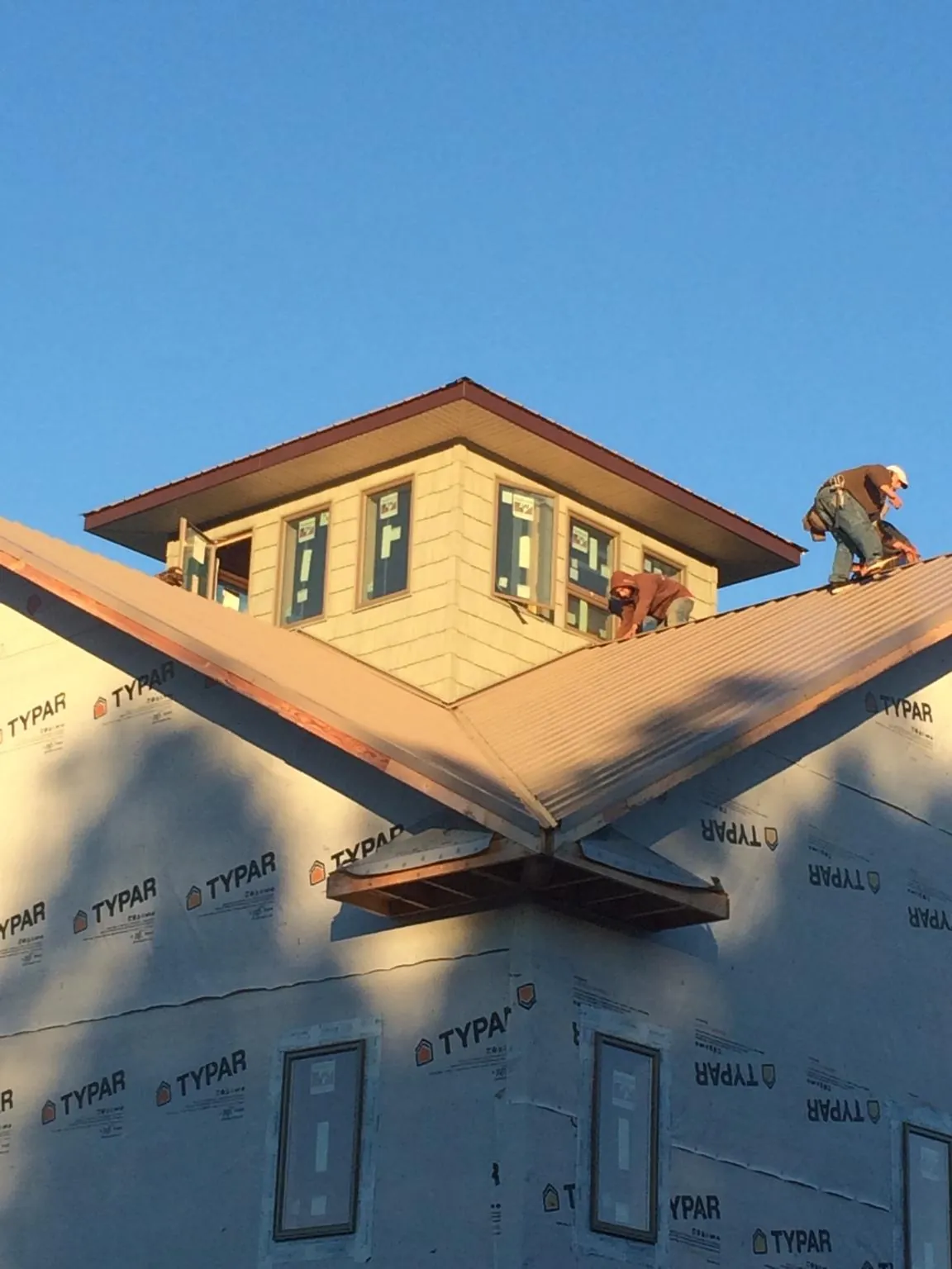 Roofers working around a rooftop cupola on a new metal roof at sunset — Roof Waterproofing in Scotts Hill by Roofing Brothers